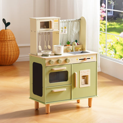 Sage green wooden play kitchen with oven, microwave, ice maker, and gingham curtain, photographed in a sunny playroom.
