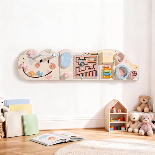 Cream elephant activity busy board mounted on the wall in a styled room with children's books and a teddy bear nearby