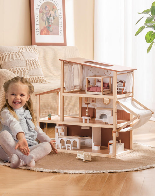 Girl sitting cross-legged and smiling beside the bohemian wooden dollhouse in a living room
