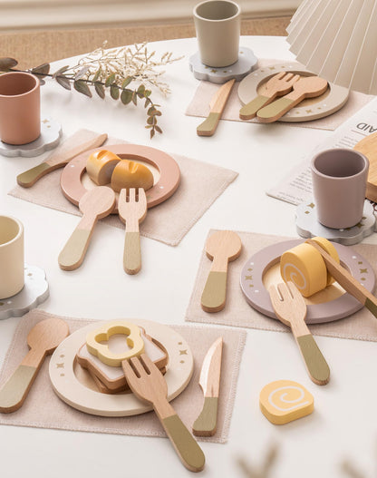 ROBUD wooden play dishes four-set arranged on linen tablecloth with wooden food pieces in airy white setting