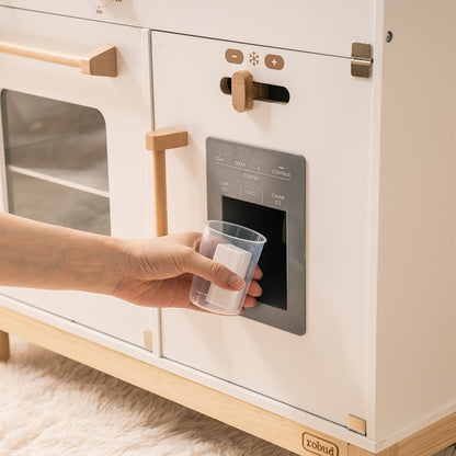 White wooden play kitchen close-up showing the ice and water dispenser panel with cube ice, chunk ice, and cold water controls